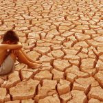 Child sit on cracked earth in the arid area